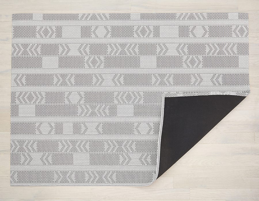 a rectangular woven floor mat made of eco friendly vinyl in shades of grey and white in a funky geometric pattern with rectangles and arrows