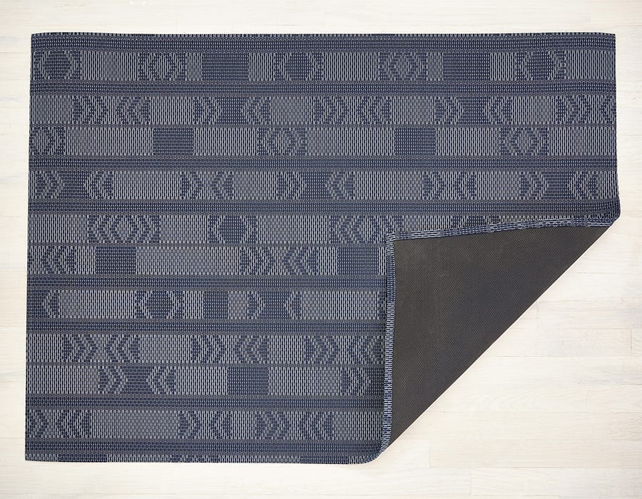 a rectangular woven floor mat made of eco friendly vinyl in shades of navy in a funky geometric pattern with rectangles and arrows