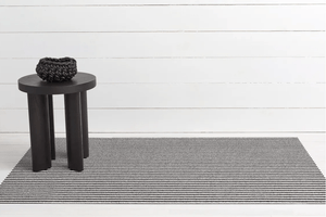Rectanguler skinny black and white striped mat on floor with white wood background for display
