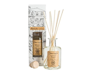 A clear, glass bottle of Lavender scented diffuser, with 7 bamboo reeds in the neck of the bottle and a lable printed with " Batons a parfum, fragrance diffuser, lavande, lavender" and the Lothantique logo. Shown with a second bottle in white packaging with black line drawings of French houses.