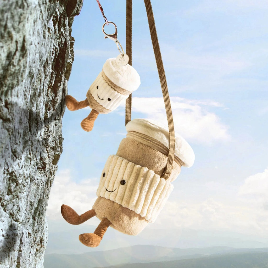 Jellycat coffee cup bags repelling down a cliff face with a cute smile