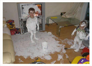 Photo of two children covered in white paint and whave created a big mess