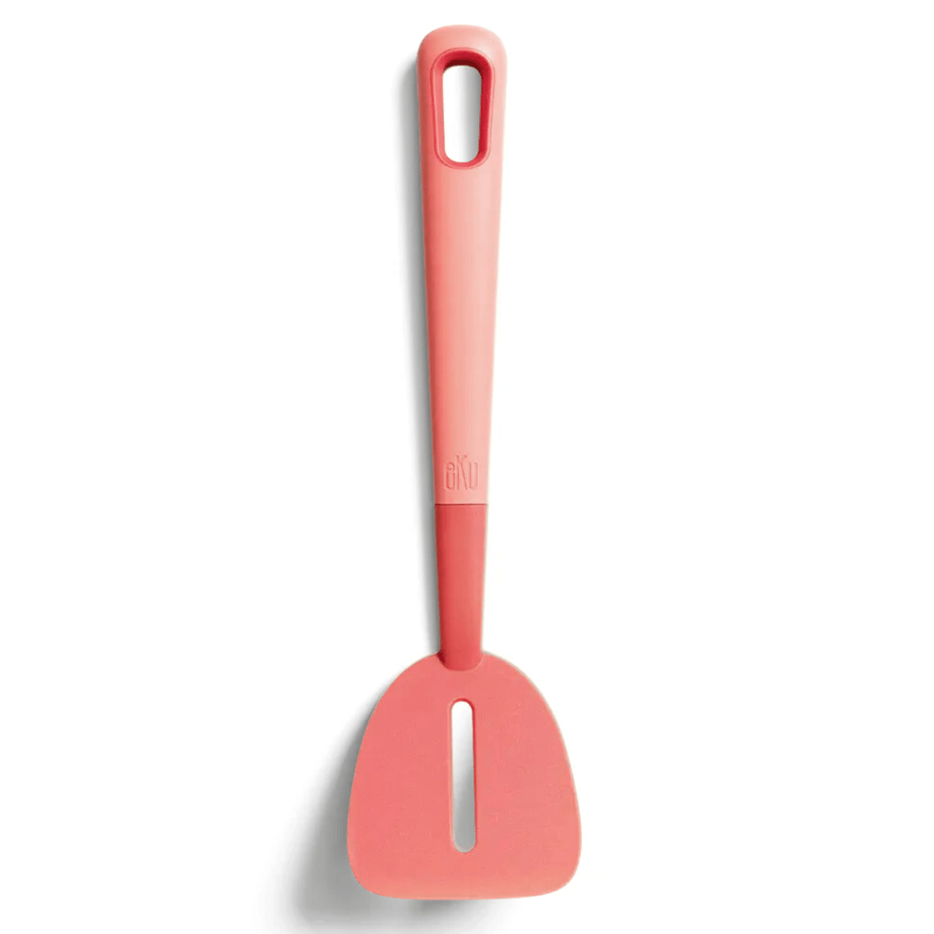 A watermelon coloured slotted turner with a sleek design on a white background, featuring an angled head and a comfortable soft grip handle. Ideal for flipping and lifting food while leaving unwanted bits behind.