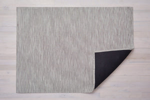 a rectangular floor mat made of plynl, an eco-friendly vinyl, in a light, slightly warm grey with white striations 