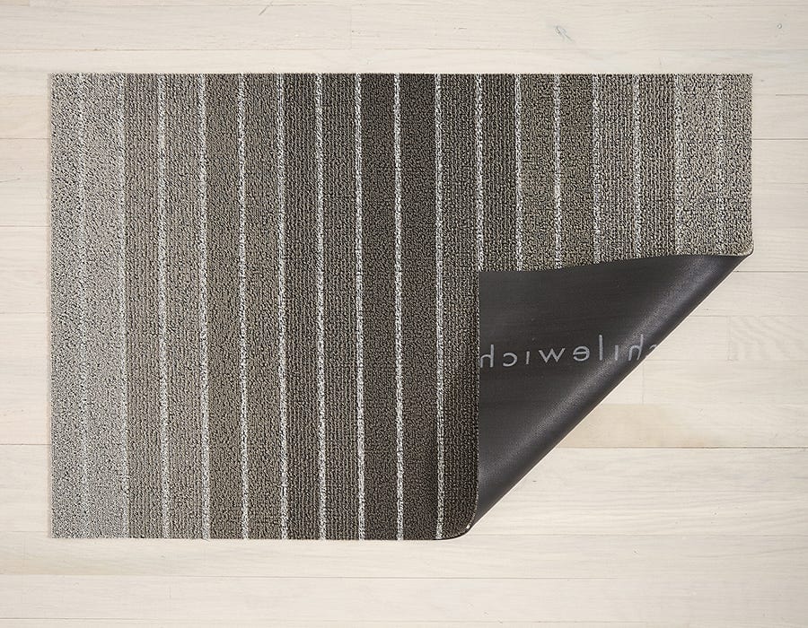a rectangular floor mat backed with black commercial rubber made of eco friendly looped vinyl yarn in a striped patter with shades of gray and white