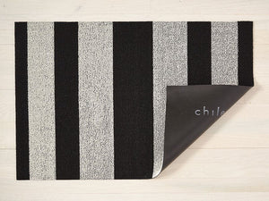 a black and white bold striped rectangular floor mat backed with black commercial rubber made of eco friendly looped vinyl yarns