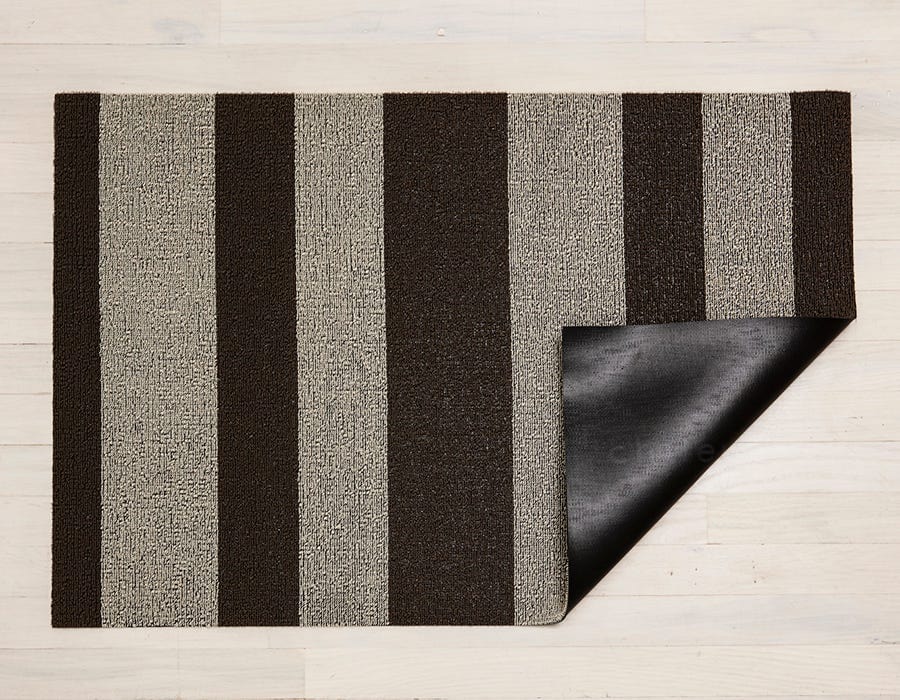 a rectangular, bold striped shag floor mat in dark brown and pale brown made of eco friendly looped vinyl yarns backed with commercial black rubber