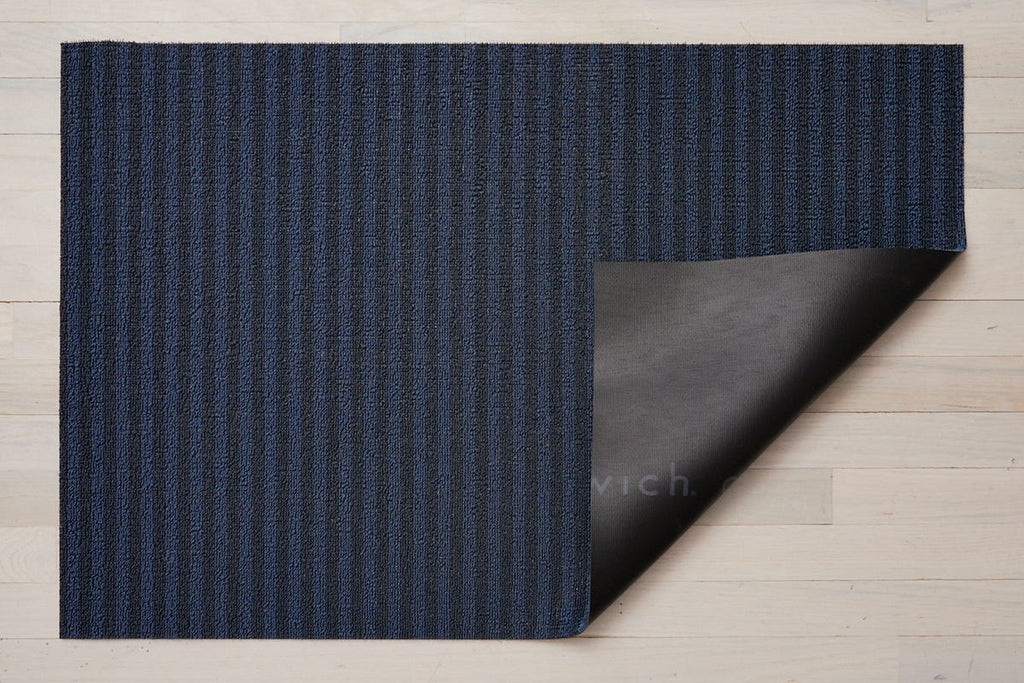 a medium blue and navy skinny striped rectangular floor mat backed with commercial black rubber made of eco friendly looped vinyl yarn
