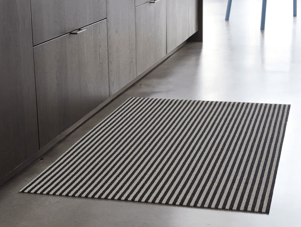 Rectanguler skinny black and white striped mat on stone floor for display