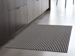 Rectanguler skinny black and white striped mat on stone floor for display
