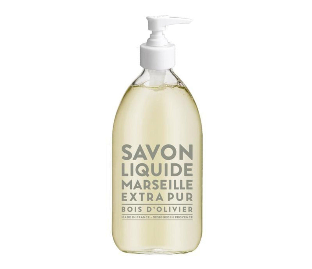 Compagnie de Provence Olive Wood liquid soap in a clear, glass 500mL botlle with pale grey block letters and a pump dispenser.