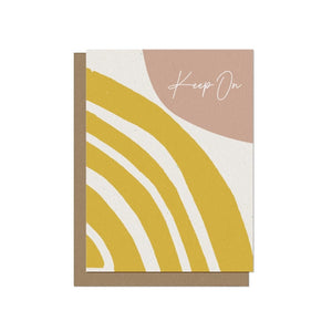 a white greeting card with an abstract design in yellow and beige with the encouraging words "keep on" interior reads "shining bright"