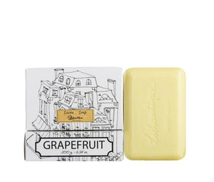 A bar of grapefruit scented soap next to its packaging, which features the Lothantique logo and a black and white line drawing of French-style houses.