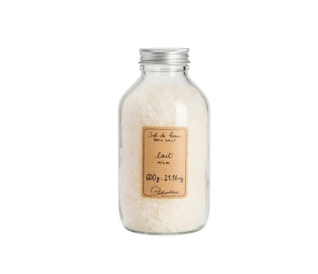 A clear, glass bottle of milk-scented bath salts, with a beige label printed with the words "sel de bain, bath salt, lait milk, 600g-21.16oz" and the Lothantique logo