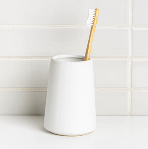 white cylindrical toothbrush holder 
