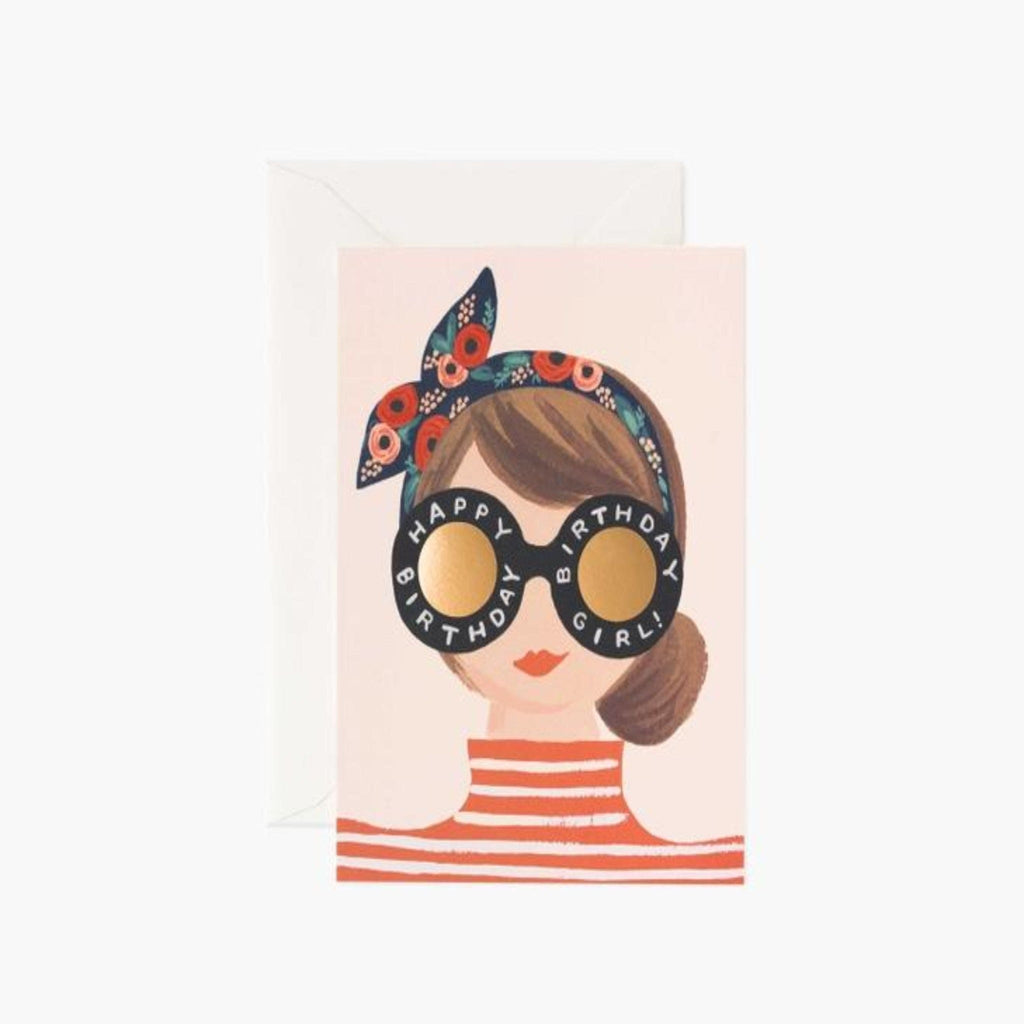 White card with illustrated portarit of a lady with a floral headband, a red and white striped top, red lipstick, a brown bun and big black and gold glasses that reads " Happy birthday, birthday girl"